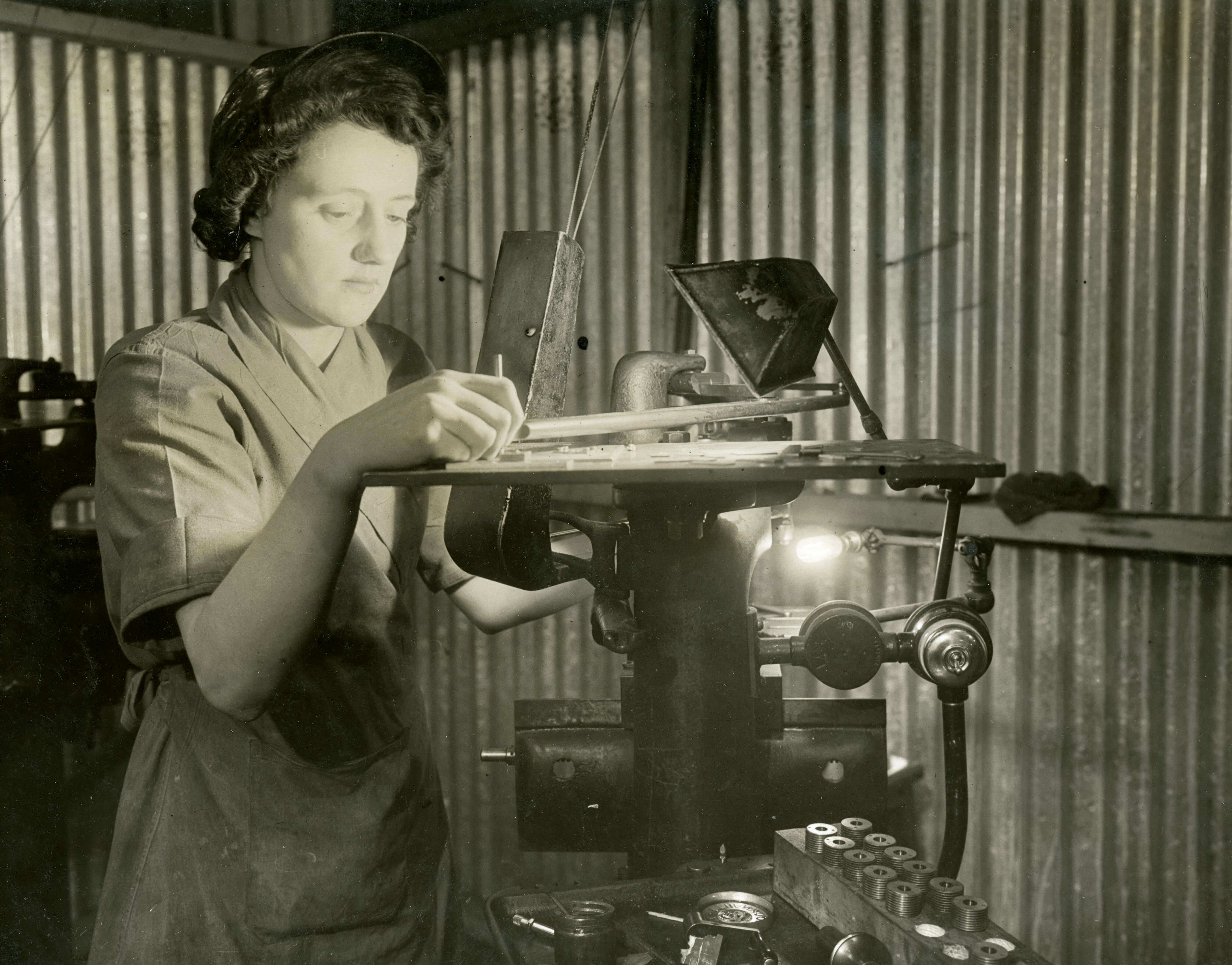 Woman operating a lathe machine in the Royal Mint factory