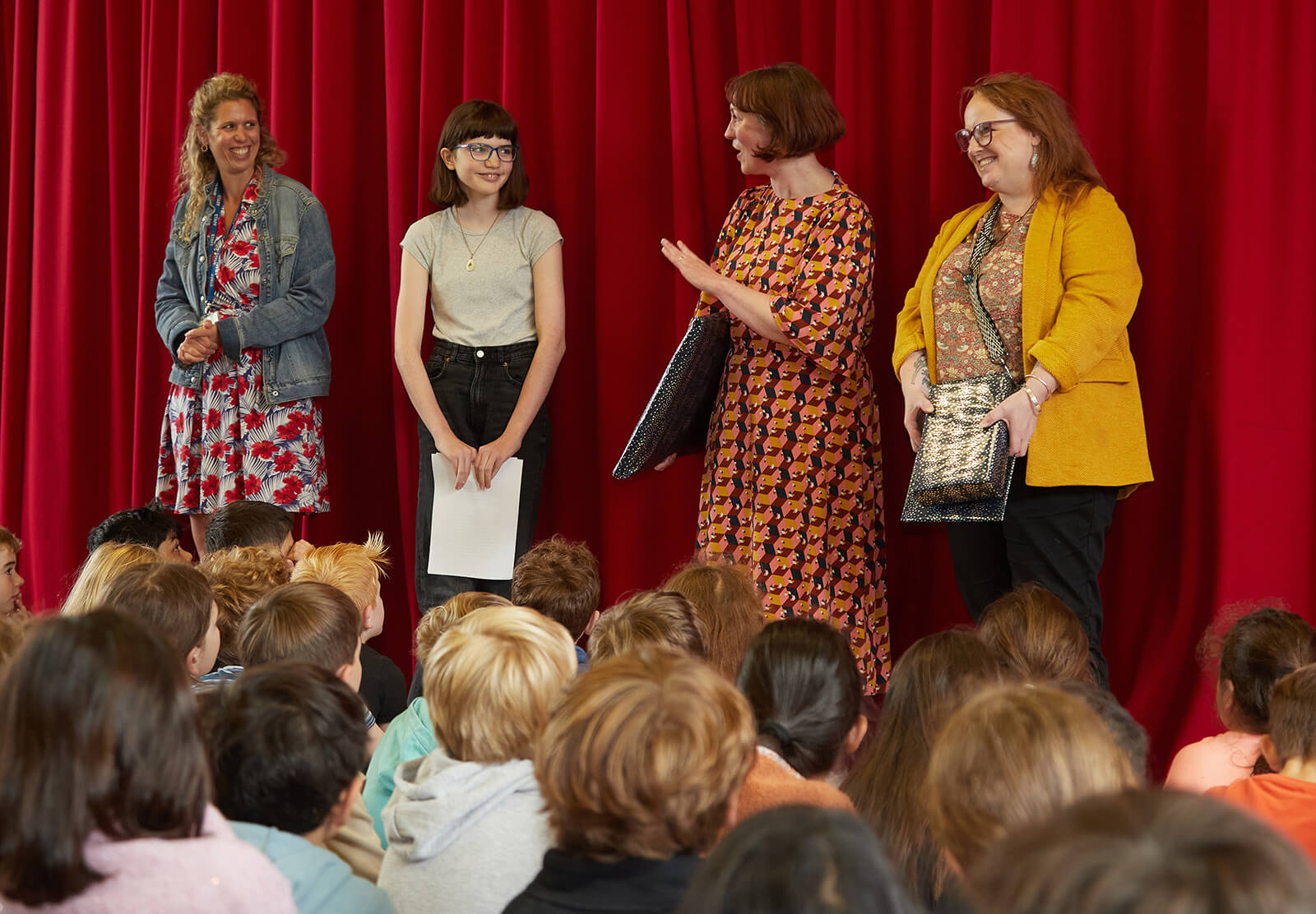 Several members of the Royal Mint Museum team are presenting a child with a framed copy of their illustrated short story entry