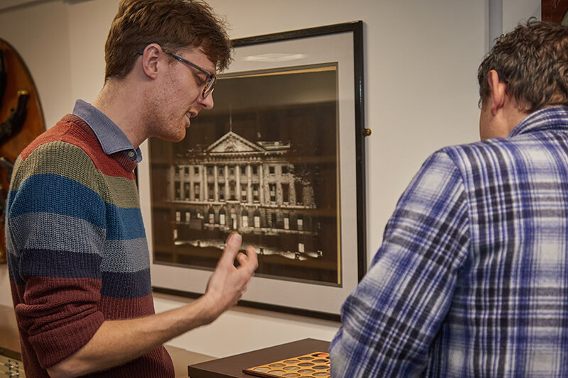 Chris Barker and Richard Blakemore discussing a tray of coins in the Royal Mint Museum